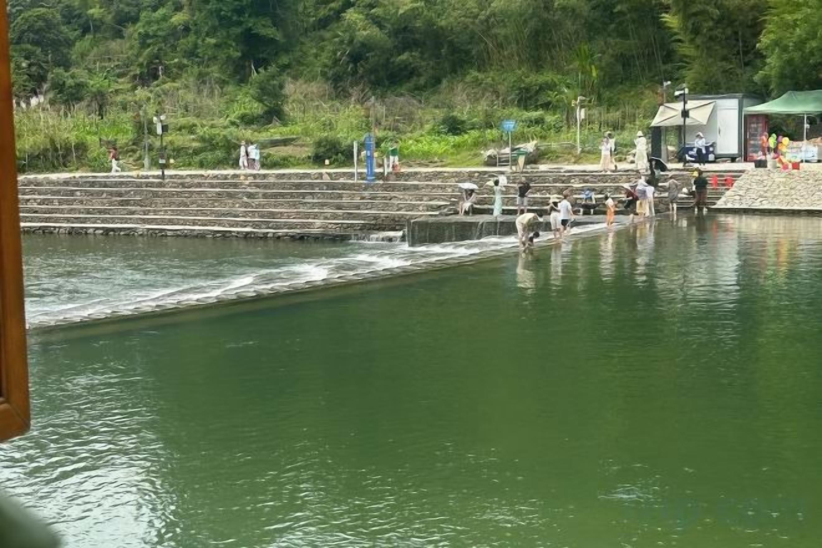 A water body with steps leading to a platform, surrounded by greenery.