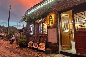 A traditional building with a wooden door and signage, a stone-paved entrance, and a menu board outside. - Fuliang Yaoli Muxiangju Inn (Fuliang)