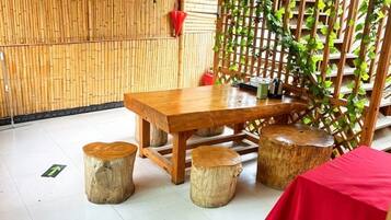 A wooden table with stools, a red tablecloth, and a bamboo wall.