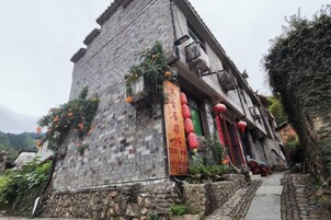 Edificio de piedra tradicional con base de piedra y tejado de baldosas, que presenta una entrada estrecha y un pequeño porche.