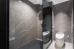 Une salle de bain moderne dotée d’une douche à parois de verre, de toilettes et d’un bidet.