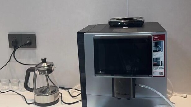 Une machine à café dotée d’une verseuse en verre et d’un bac de récupération, et qui est branchée sur une prise de courant.