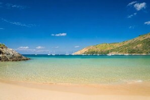 A beach with clear water, boats, and hills. - Kata Bai D (Phuket)