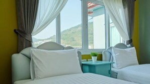Une chambre d’hôtel avec deux lits, une petite table avec une plante et une vue sur une montagne.