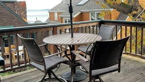 A wooden deck with a round table and four chairs, an umbrella, and a view of houses and a body of water. - Cozy quiet & relaxing hide-a-way in the heart of Sausalito's ‘Hurricane Gulch.’ (Sausalito)