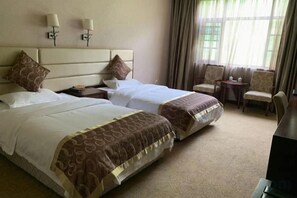 Una habitación de hotel con dos camas, una mesita de noche, una silla y una pequeña mesa.
