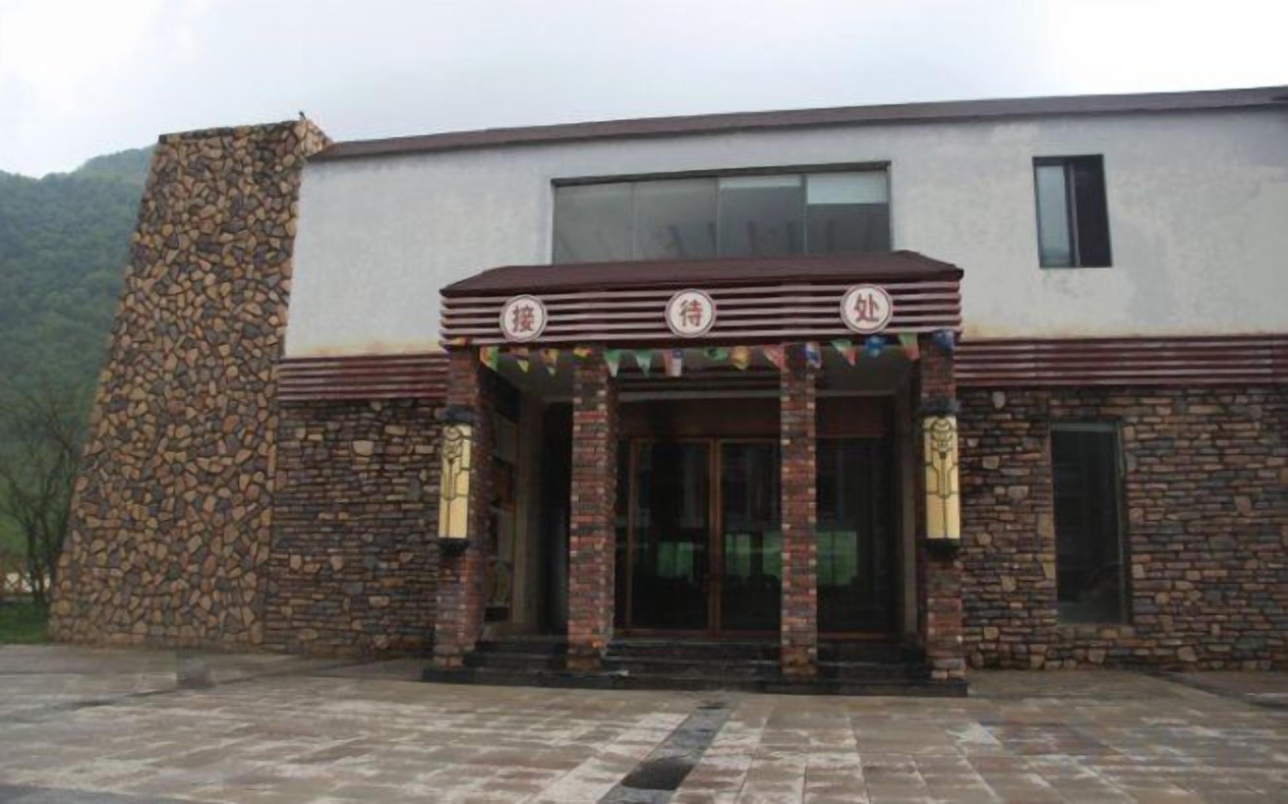 A building with a stone facade, a flat roof, and a central entrance with a decorative canopy.