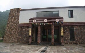 A building with a stone facade, a flat roof, and a central entrance with a decorative canopy. - Hongchiba Holiday Hotel (Wuxi County)