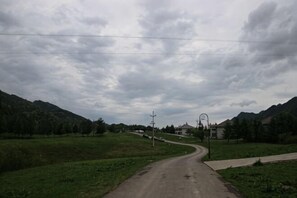A rural road curving through a green landscape with mountains in the distance and a few buildings. - Hongchiba Holiday Hotel (Wuxi County)