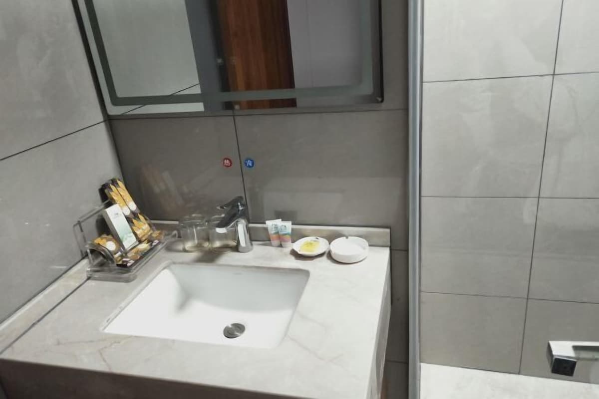 A bathroom with a white sink, a mirror, and toiletries on the counter.