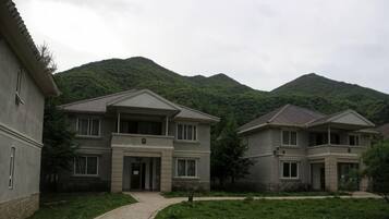 A residential building with a paved driveway and a mountain backdrop.