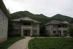 A residential building with a paved driveway and a mountain backdrop.