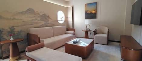 A modern living room with a sofa, a coffee table, a chair, a round table, and a painting on the wall.
