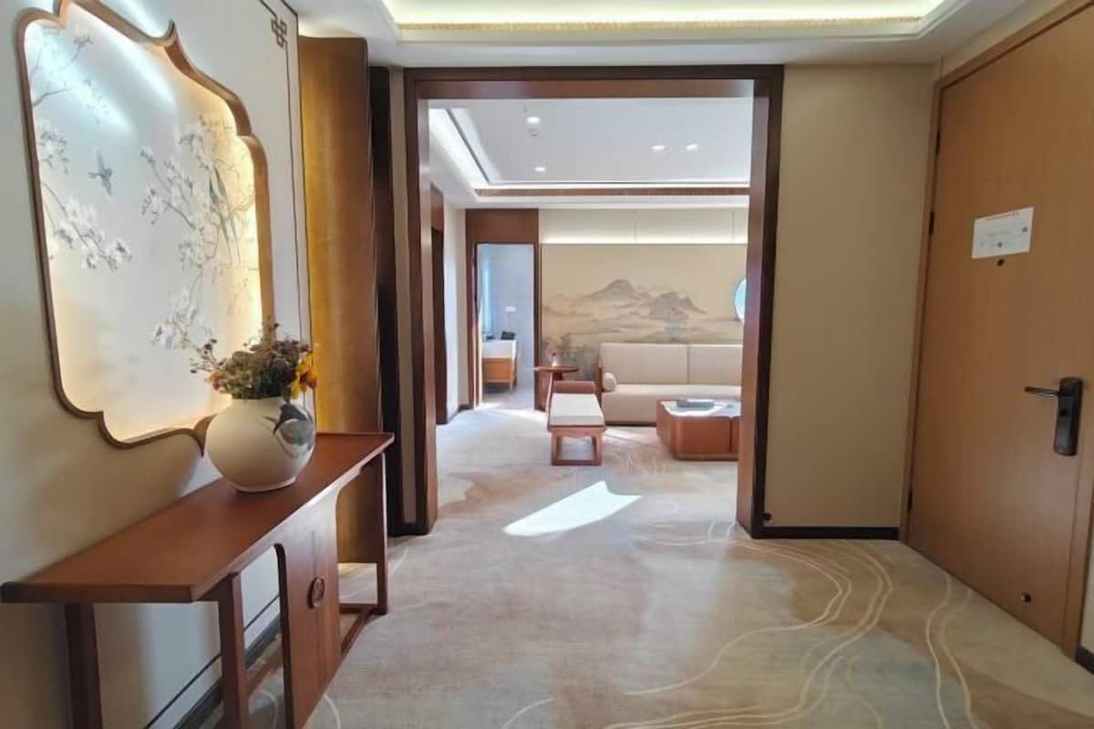 A hotel lobby with a reception desk, a wall-mounted artwork, a sofa, and a mural in the background.