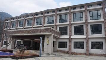 A multi-story building with a covered entrance and a parking area.