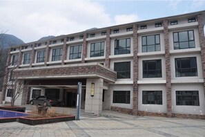 Un edificio de varios pisos con un acceso cubierto y un estacionamiento.