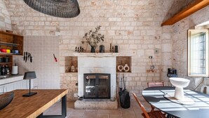 Une cuisine rustique avec des murs en briques apparentes, une cheminée, des meubles en bois et un luminaire suspendu.
