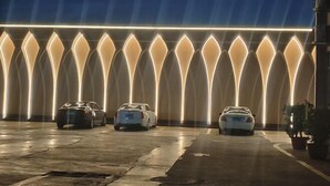A parking area with three cars and a row of illuminated arches. - Shuixiu Boutique Hotel (Quwo)