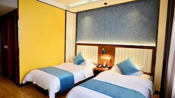 Quarto de hotel com duas camas, piso de madeira, parede grande com design texturizado e mesa de cabeceira com abajur.