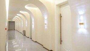 A long, narrow hallway with white walls and a shiny floor, leading to a door at the end. - Shuixiu Boutique Hotel (Quwo)