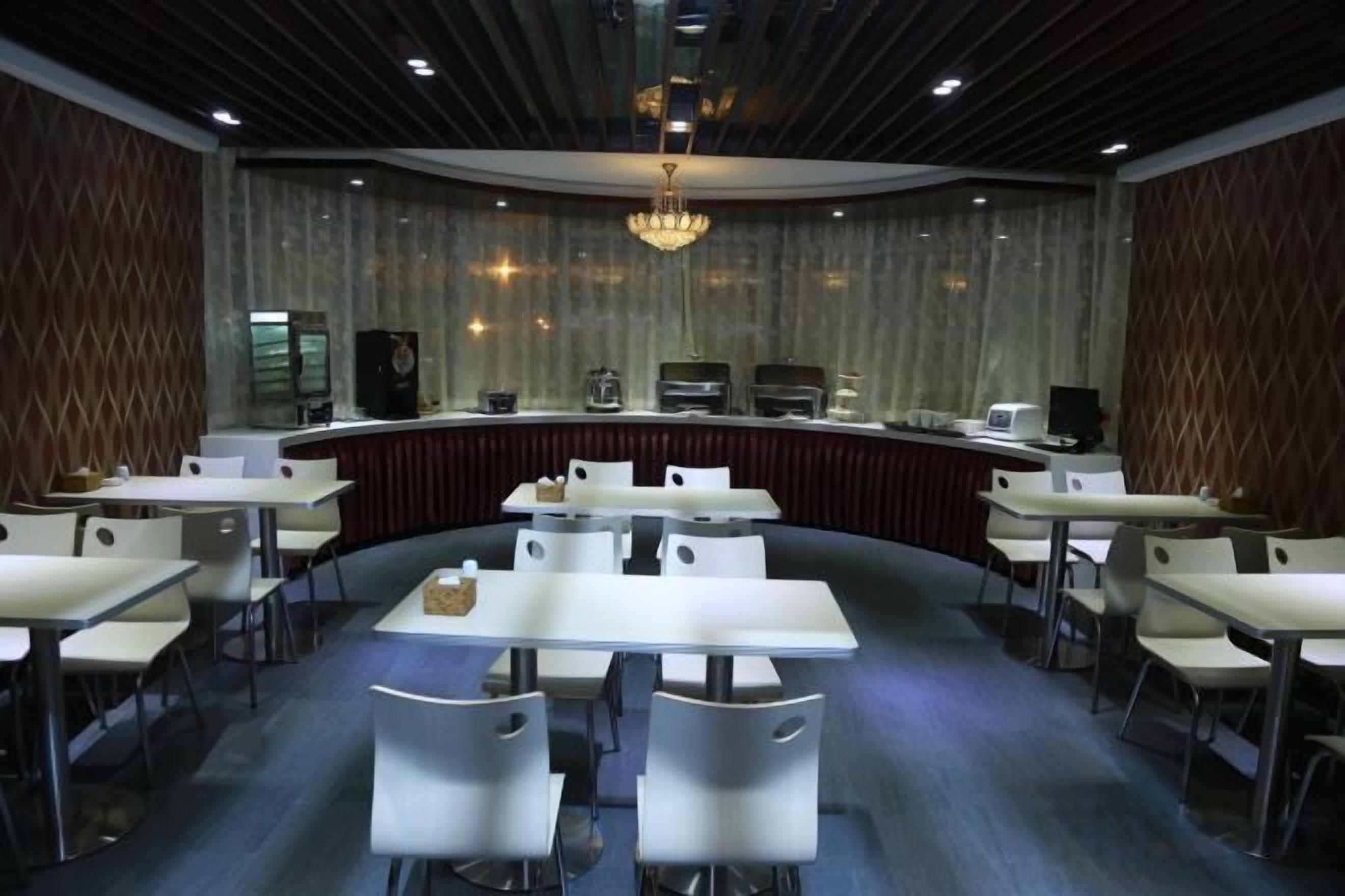 A conference room with a curved layout, white tables, and chairs, a central bar area, and a chandelier.