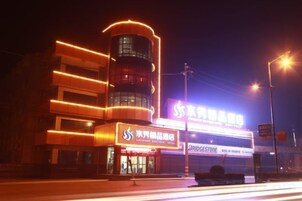 Un edificio con señalización iluminada, una entrada destacada y una estructura vertical.