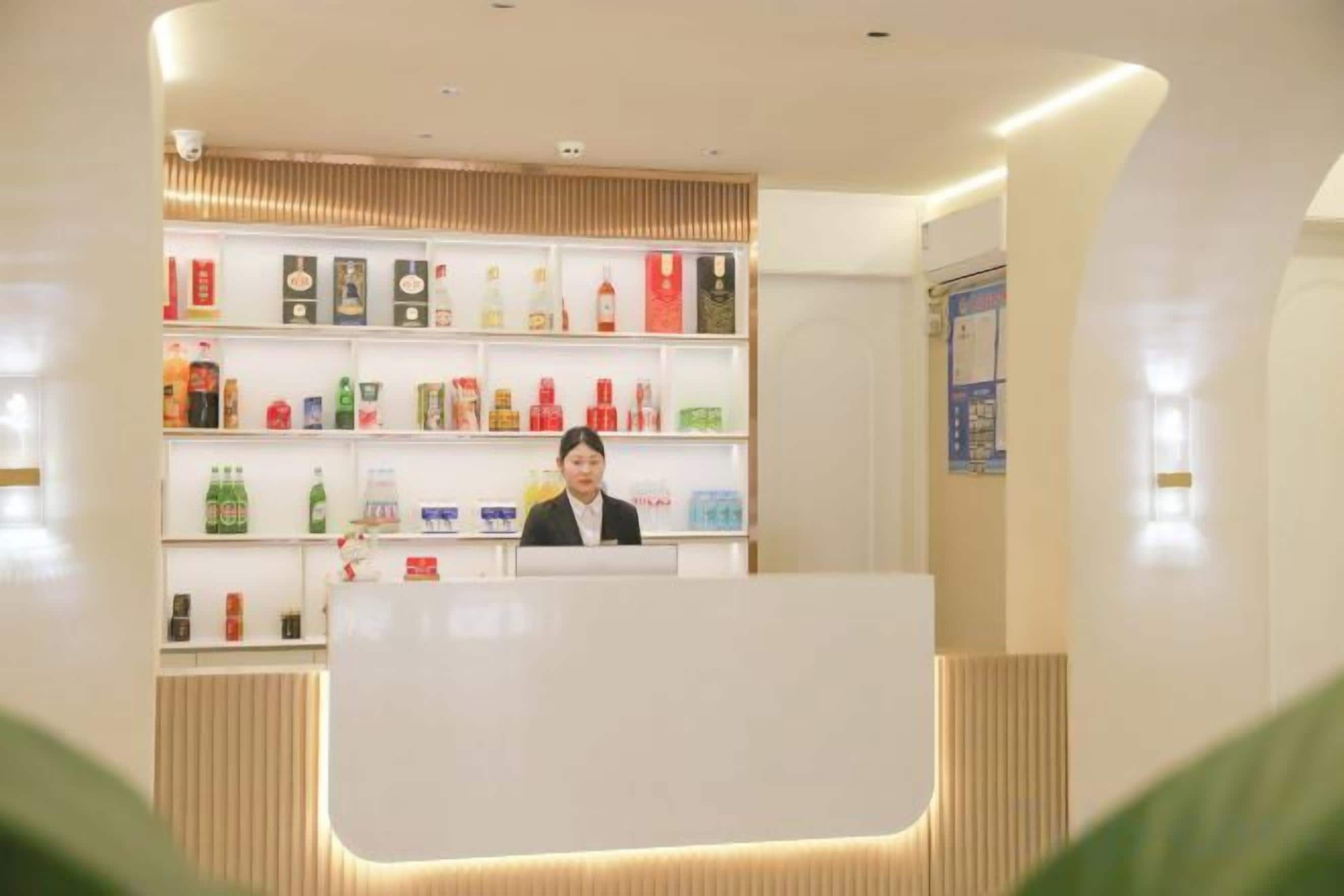 A reception area with a counter and shelves stocked with various bottled beverages.