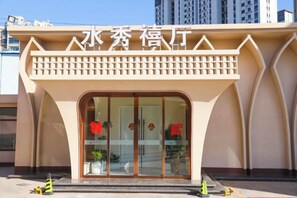 A building with a beige facade and a large arched entrance. - Shuixiu Boutique Hotel (Quwo)