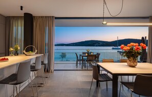 Enjoy meals with a view of the water from this dining area featuring a long table and comfortable seating.