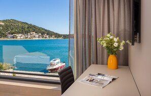 Enjoy a tranquil view of the coastal town from the large window, with a comfortable seating area and a stylish vase with fresh flowers.