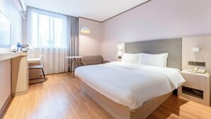 A modern hotel room with a large bed, a desk, a chair, and a small table. - HanTing Hotel (Ganzhou Jiangnan Songcheng Wenming Avenue) (Ganzhou)
