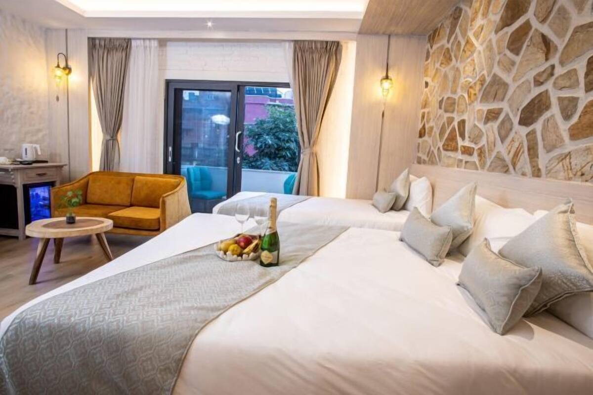 Une chambre d’hôtel avec un lit, un canapé, une petite table et un mur en pierre.