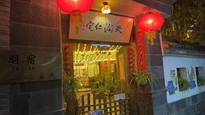 Edificio chino tradicional con letrero, farolillos rojos y plantas en macetas.