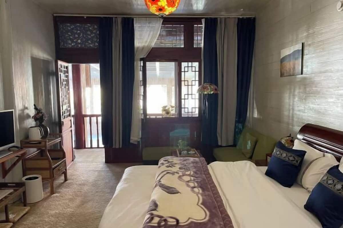 A hotel room with a bed, a desk, a chair, a TV, and a window with curtains.