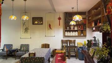 Una habitación tradicional con zona de comedor, una estantería y lámparas colgantes.