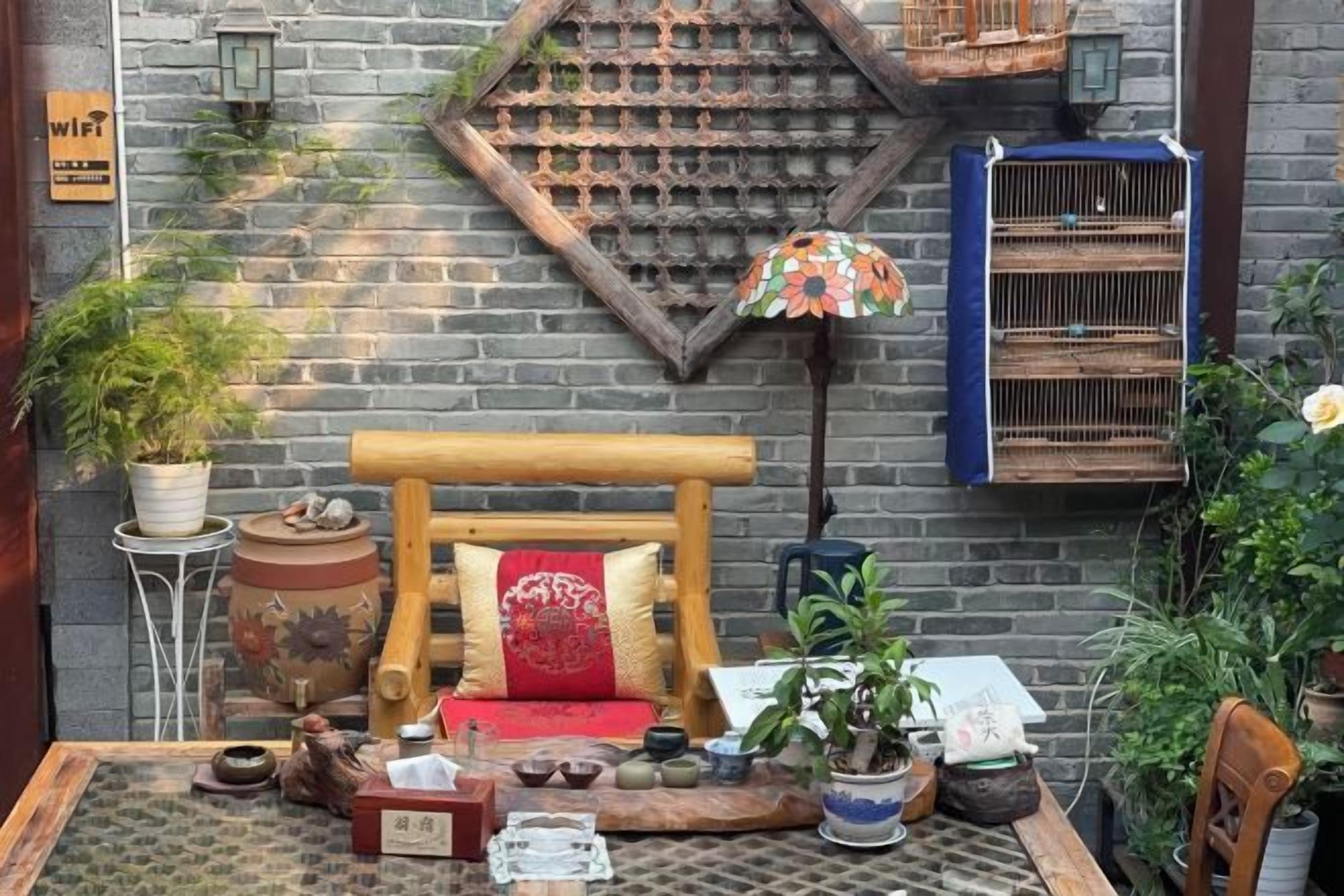 A rustic outdoor seating area with a wooden bench, potted plants, and a decorative wall.