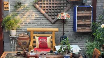 A rustic outdoor seating area with a wooden bench, potted plants, and a decorative wall.