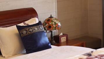 A neatly made bed with a headboard, a decorative lamp, and a tissue box on a bedside table.