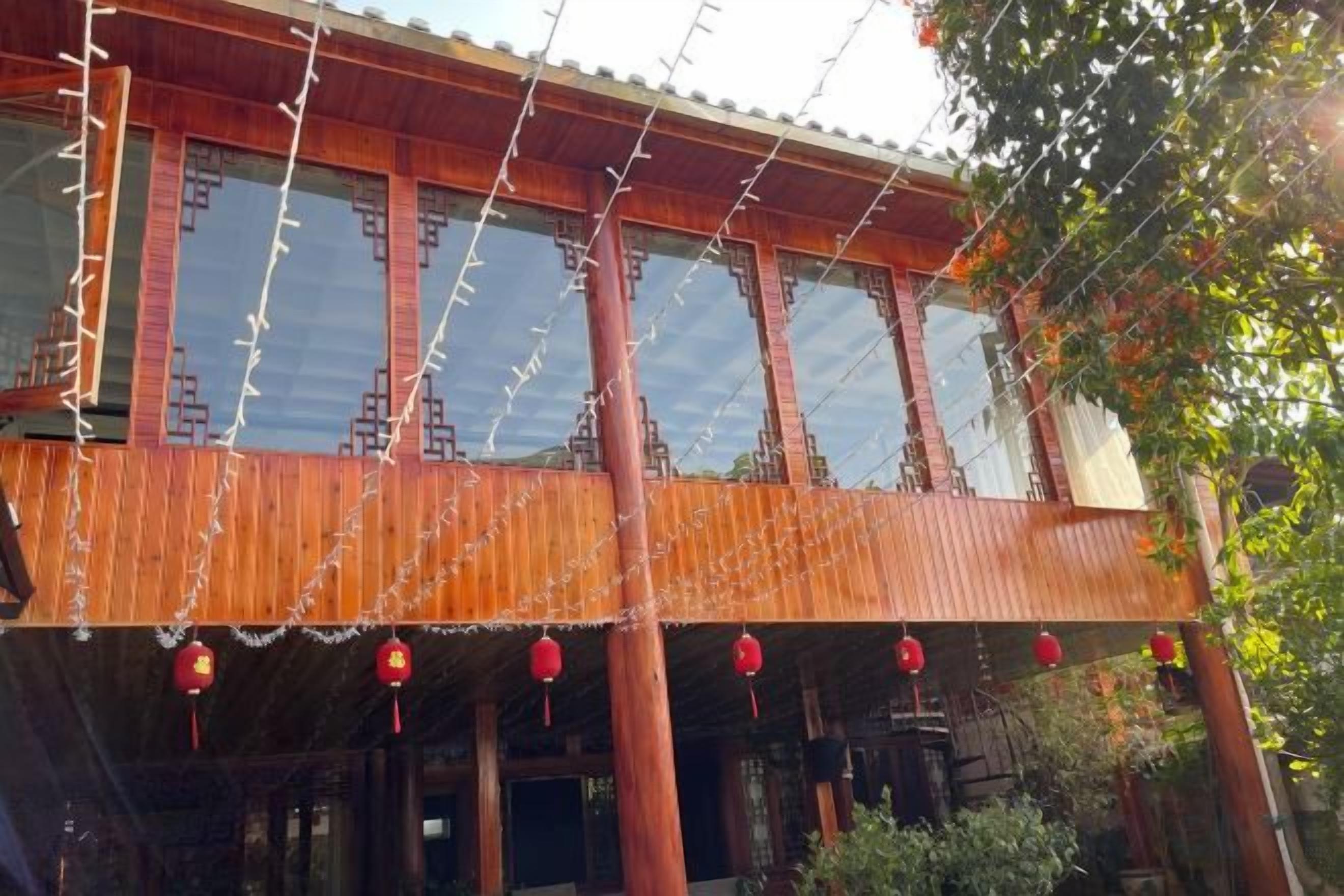 A traditional wooden building with a balcony, red lanterns, and a clear sky.
