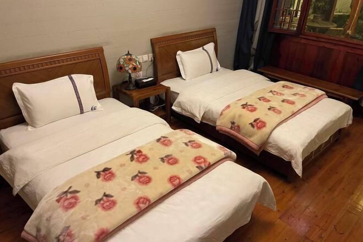 Two single beds with wooden headboards, white bedding, and floral-patterned blankets.