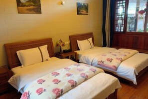 A room with two beds, each with white bedding and floral patterns. There are wooden headboards and nightstands with lamps. The room has a wooden floor and a window with a view of the outside. - Tengchong Yusu Inn (Tengchong)
