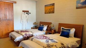 A room with two beds, wooden headboards, a wooden door, and a wall-mounted coat rack.