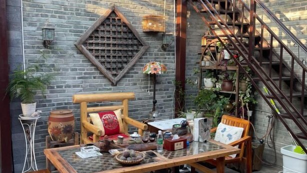 Un interior rústico con una mesa de madera, sillas y una pared de ladrillo.