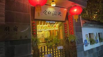 A traditional building with a sign indicating a restaurant or eatery. There are red lanterns hanging above the entrance, and the building has a brick facade.