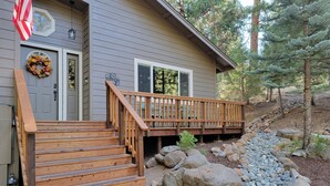 A wooden deck leading to a house with a front door, a mailbox, and a mailbox slot. - Lake Almanor West home in a peaceful setting just minutes from the lake (Chester)
