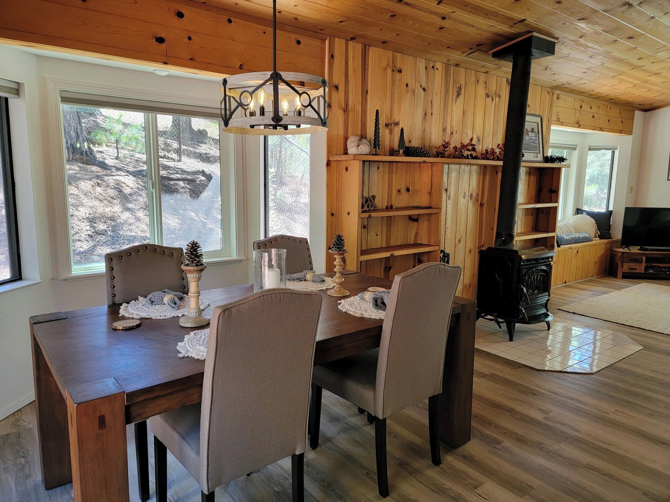 Un coin repas avec une table et des chaises en bois, un lustre et une cheminée.