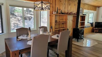 A dining area with a wooden table and chairs, a chandelier, and a fireplace.