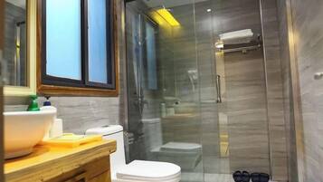Un baño moderno con ducha envuelta en vidrio, tocador de madera y váter blanco.