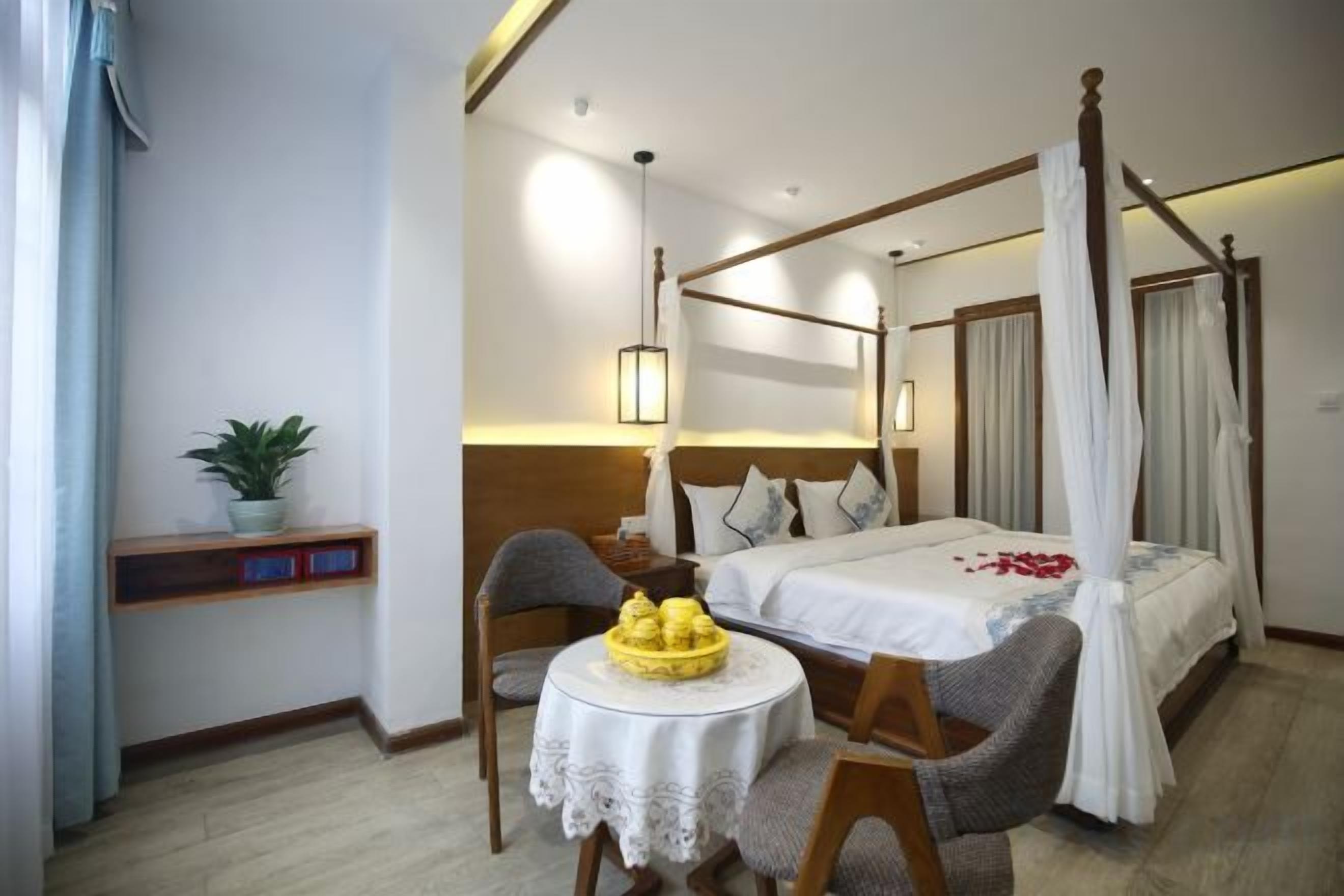 A four-poster bed with a canopy, a bedside table with a lamp, and a chair.