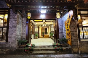 A traditional building entrance with a tiled pathway leading to a wooden door.